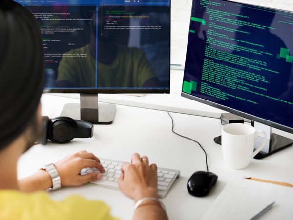 Eine Person arbeitet an zwei Bildschirmen.