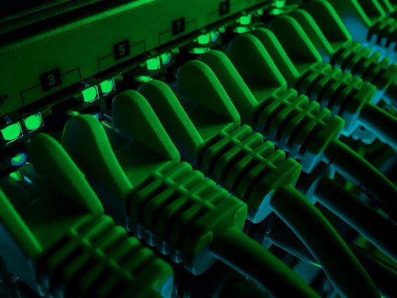 Datenschutz und Datensicherheit in Unternehmen Server Rack mit gepatchten Datenkabeln und grün leuchtenden Dioden