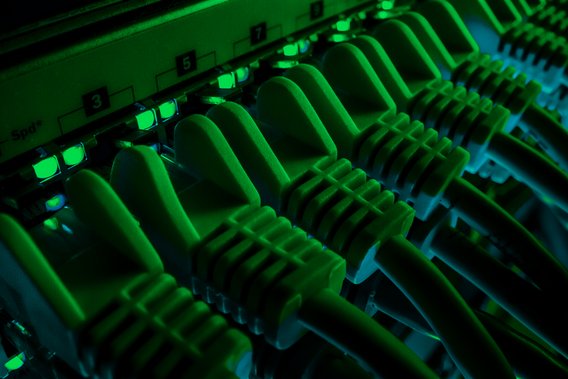 Server Rack mit gepatchten Datenkabeln und grün leuchtenden Dioden