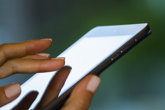 Die Hand einer Frau bedient die Oberfläche einer Mobilen Anwendung auf einem Smartphone